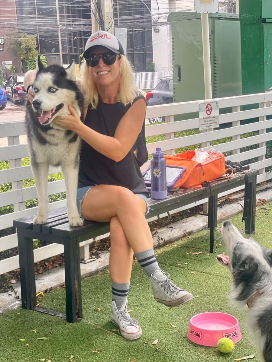 Jo Urbanek sitting on a bench with a dog in a Bangkok park